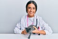 Young hispanic veterinary girl smiling happy holding cat working at the clinic