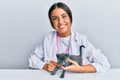 Young hispanic veterinary girl smiling happy holding cat working at the clinic