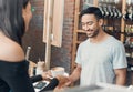 Young hispanic waiter serving a cup of coffee to a customer while working in a cafe. Friendly barista and coffeeshop Royalty Free Stock Photo