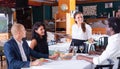 Young hispanic waitress serving meals to company in restaurant Royalty Free Stock Photo