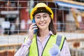 Young hispanic woman architect talking on the smartphone holding blueprints at street Royalty Free Stock Photo