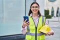 Young hispanic woman architect using smartphone at street Royalty Free Stock Photo