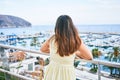 Young hispanic woman on back view leaning on balustrade looking port landscape