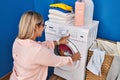 Young hispanic woman on back view washing clothes at laundry room