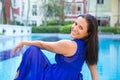 Young hispanic woman in blue dress relaxing by the swimming pool Royalty Free Stock Photo