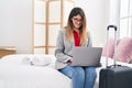 Young hispanic woman business worker using laptop sitting on bed at hotel room Royalty Free Stock Photo