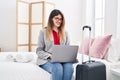 Young hispanic woman business worker using laptop sitting on bed at hotel room Royalty Free Stock Photo