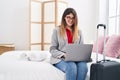 Young hispanic woman business worker using laptop sitting on bed at hotel room Royalty Free Stock Photo