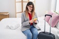 Young hispanic woman business worker using smartphone sitting on bed at hotel room Royalty Free Stock Photo