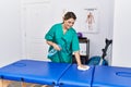 Young hispanic woman cleaning massage table at physiotherapy clinic Royalty Free Stock Photo