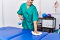 Young hispanic woman cleaning massage table at physiotherapy clinic Royalty Free Stock Photo