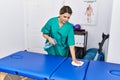 Young hispanic woman cleaning massage table at physiotherapy clinic Royalty Free Stock Photo