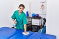 Young hispanic woman cleaning massage table at physiotherapy clinic Royalty Free Stock Photo