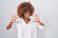 Young hispanic woman with curly hair standing over white background showing and pointing up with fingers number ten while smiling Royalty Free Stock Photo