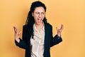 Young hispanic woman with curly hair wearing business clothes crazy and mad shouting and yelling with aggressive expression and Royalty Free Stock Photo