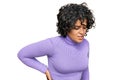 Young hispanic woman with curly hair wearing casual clothes suffering of backache, touching back with hand, muscular pain Royalty Free Stock Photo
