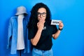 Young hispanic woman with curly hair wearing staff t shirt holding open banner covering mouth with hand, shocked and afraid for Royalty Free Stock Photo