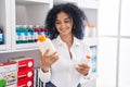 Young hispanic woman customer smiling confident choosing sunscreen lotion at pharmacy Royalty Free Stock Photo