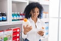 Young hispanic woman customer smiling confident choosing sunscreen lotion at pharmacy Royalty Free Stock Photo