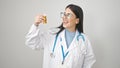 Young hispanic woman doctor holding pills over isolated white background Royalty Free Stock Photo