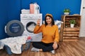 Young hispanic woman doing laundry showing and pointing up with fingers number four while smiling confident and happy