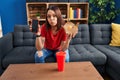 Young hispanic woman eating fast food showing smartphone screen looking at the camera blowing a kiss being lovely and sexy