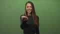 Young hispanic woman extending open palm offering gesture in studio with solid green backdrop; invitation trust Royalty Free Stock Photo