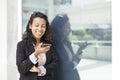 Young Hispanic woman in formal dress using smiling mobile phone outdoors Royalty Free Stock Photo