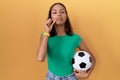 Young hispanic woman holding ball mouth and lips shut as zip with fingers