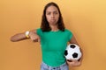 Young hispanic woman holding ball pointing down looking sad and upset, indicating direction with fingers, unhappy and depressed Royalty Free Stock Photo