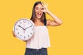 Young hispanic woman holding big clock smiling happy doing ok sign with hand on eye looking through fingers Royalty Free Stock Photo