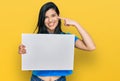 Young hispanic woman holding blank empty banner pointing finger to one self smiling happy and proud