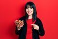 Young hispanic woman holding bowl of chestnuts smiling happy pointing with hand and finger Royalty Free Stock Photo