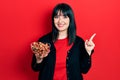 Young hispanic woman holding bowl of chestnuts smiling happy pointing with hand and finger to the side Royalty Free Stock Photo