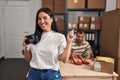 Young hispanic woman holding camera working at small business ecommerce smiling happy pointing with hand and finger to the side Royalty Free Stock Photo