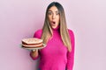 Young hispanic woman holding carrot cake scared and amazed with open mouth for surprise, disbelief face Royalty Free Stock Photo