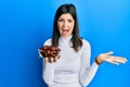 Young hispanic woman holding dates bowl celebrating achievement with happy smile and winner expression with raised hand