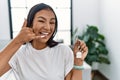 Young hispanic woman holding keys of new home smiling doing phone gesture with hand and fingers like talking on the telephone Royalty Free Stock Photo