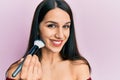 Young hispanic woman holding makeup brush and blush looking positive and happy standing and smiling with a confident smile showing Royalty Free Stock Photo