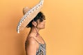 Young hispanic woman holding mexican hat looking to side, relax profile pose with natural face with confident smile