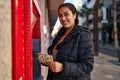 Young hispanic woman holding money of automatic teller bank machine at street Royalty Free Stock Photo