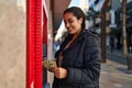 Young hispanic woman holding money of automatic teller bank machine at street Royalty Free Stock Photo