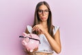 Young hispanic woman holding piggy bank with glasses and coin depressed and worry for distress, crying angry and afraid Royalty Free Stock Photo