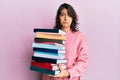 Young hispanic woman holding a pile of books depressed and worry for distress, crying angry and afraid Royalty Free Stock Photo