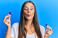 Young hispanic woman holding poker chips making fish face with mouth and squinting eyes, crazy and comical Royalty Free Stock Photo