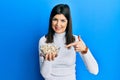 Young hispanic woman holding pumpkin seeds bowl smiling happy pointing with hand and finger Royalty Free Stock Photo