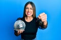 Young hispanic woman holding shiny disco ball annoyed and frustrated shouting with anger, yelling crazy with anger and hand raised Royalty Free Stock Photo