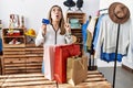 Young hispanic woman holding shopping bags and credit card at clothing store amazed and surprised looking up and pointing with Royalty Free Stock Photo