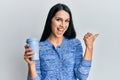 Young hispanic woman holding take away coffee pointing thumb up to the side smiling happy with open mouth Royalty Free Stock Photo