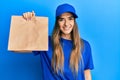 Young hispanic woman holding take away paper bag looking positive and happy standing and smiling with a confident smile showing Royalty Free Stock Photo